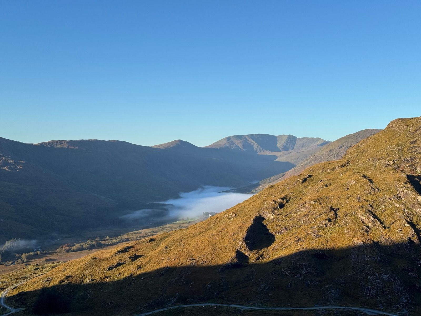 Morning mist lying in a valley below sunlit mountain slopes
