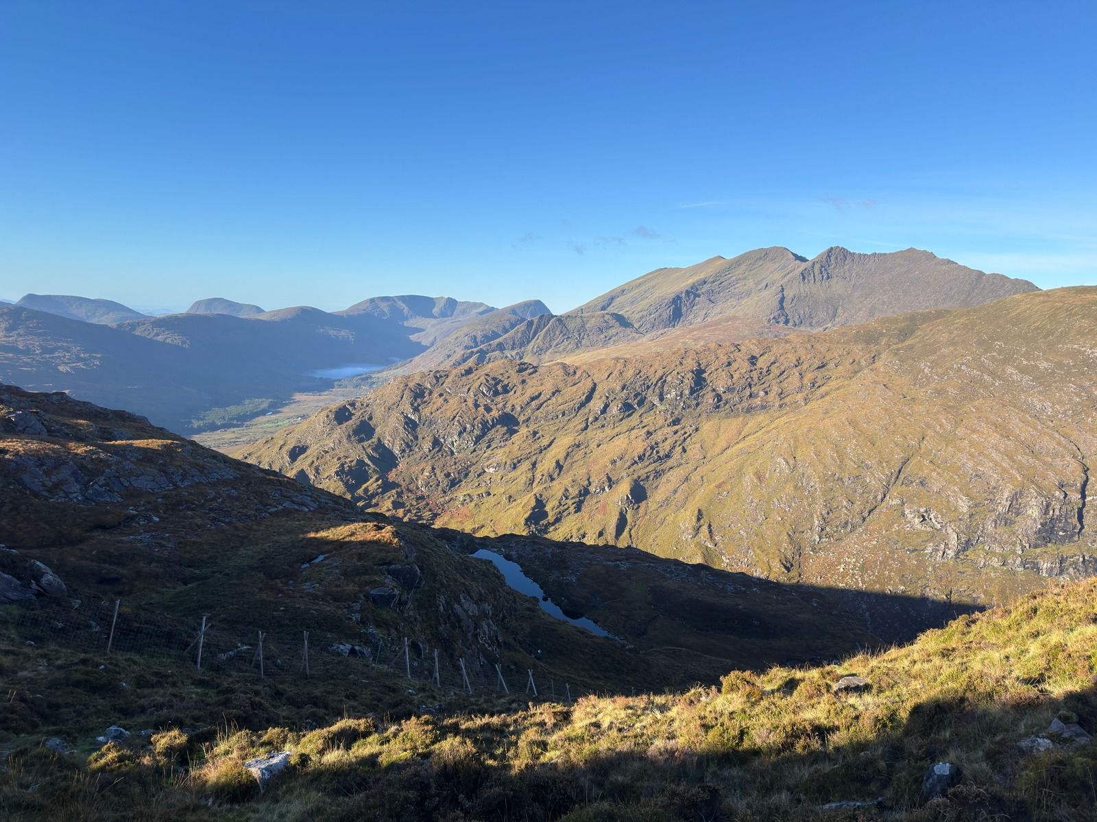 Mountain ridges across a deep valley, with mist in the lowlands and a sunlit slope in front