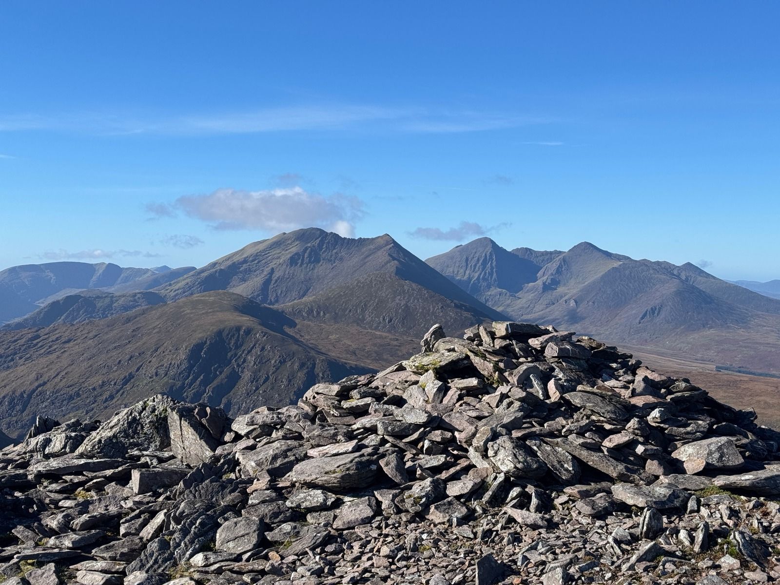 A broad heap of grey slate stones in the foreground, with mountains beyond