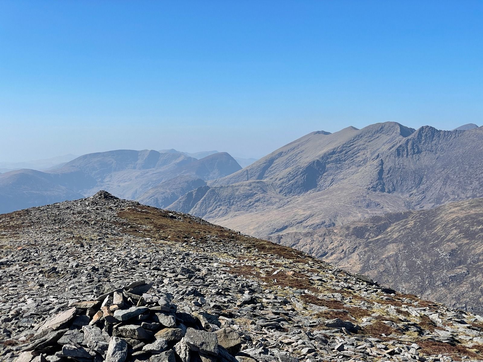 A cairn on a slate summit with the Reeks on the horizon