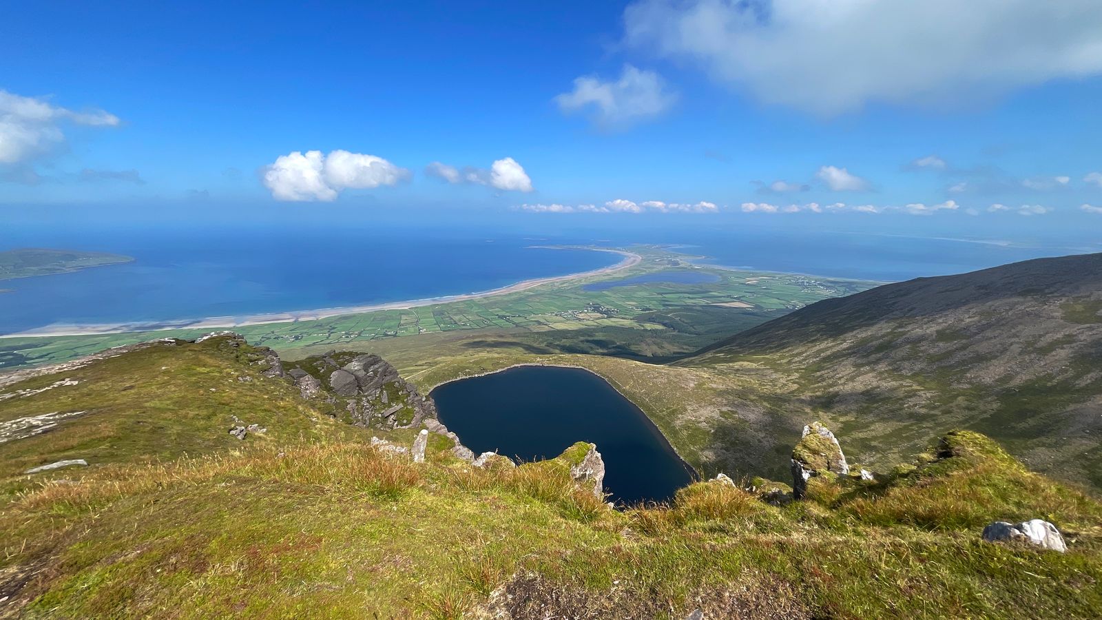 A corrie lough below the grassy crest with the Maharees stretching into the Atlantic