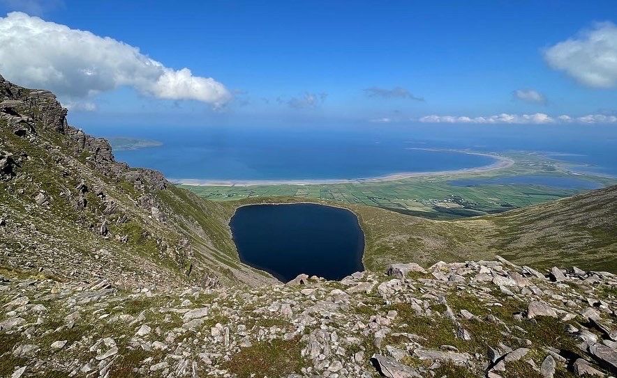A mountain lough enclosed by steep ground beneath a clear blue sky