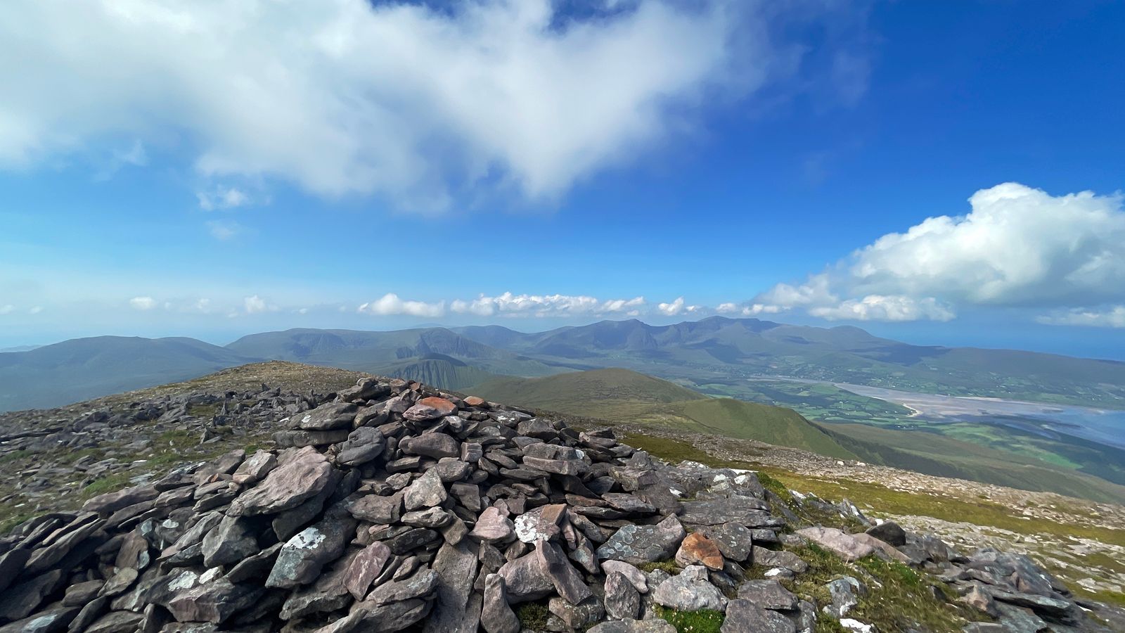 The summit cairn on Beenoskee with the Dingle mountains beyond