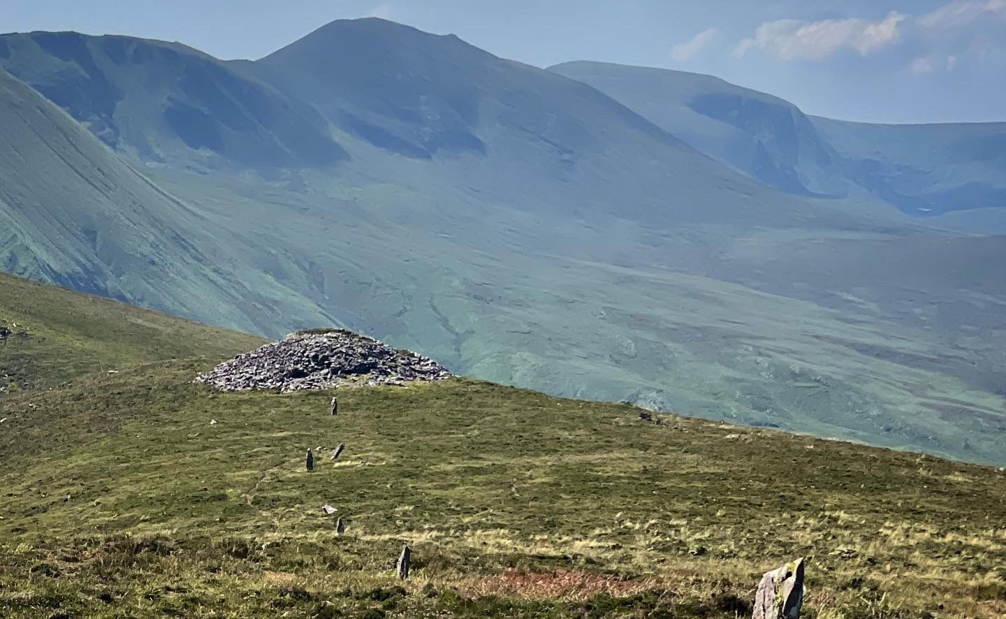 Cú Chulainn’s House with a line of upright stones crossing the hillside and mountain ridges behind