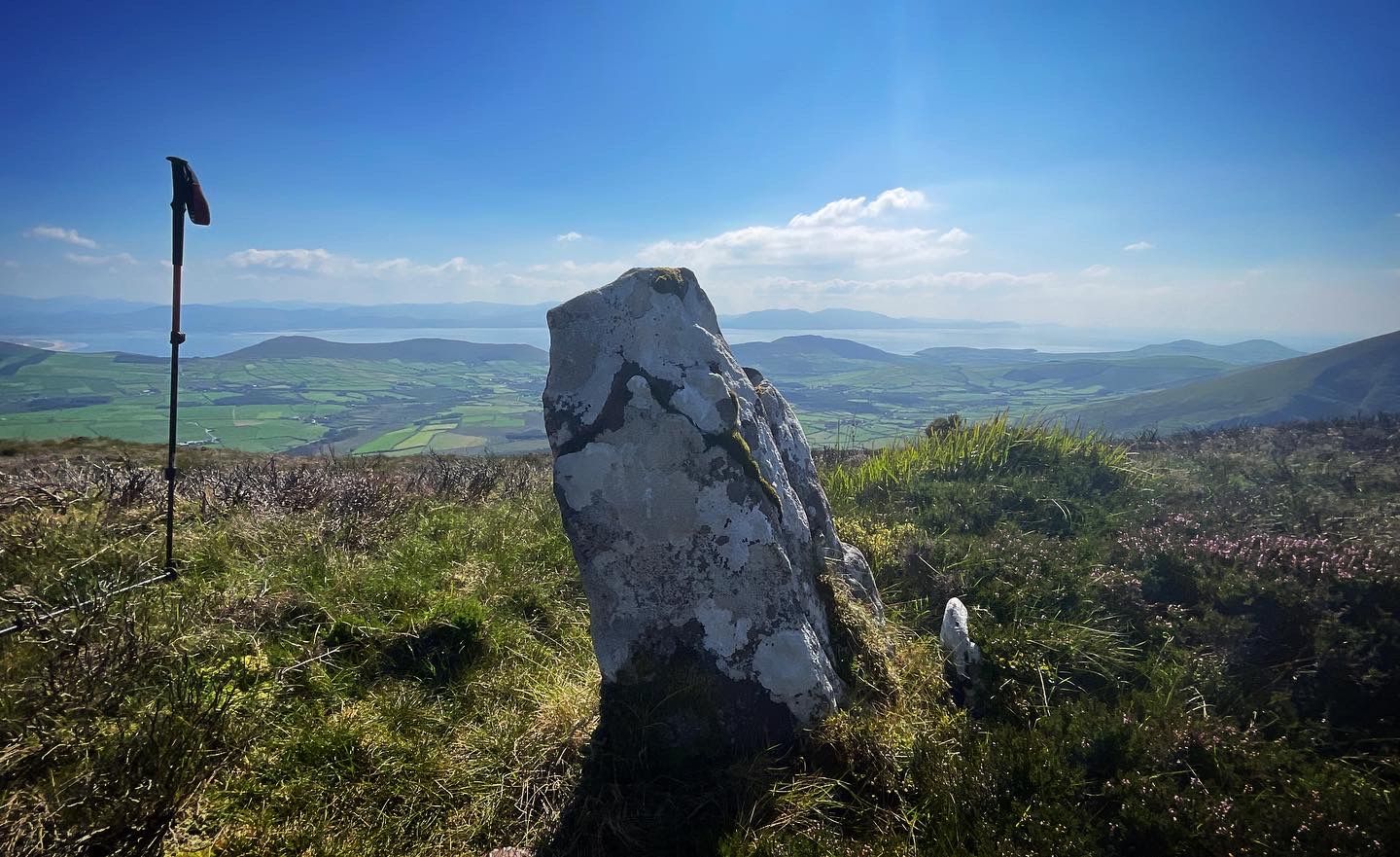 A weathered upright stone looking over farmland towards the Atlantic