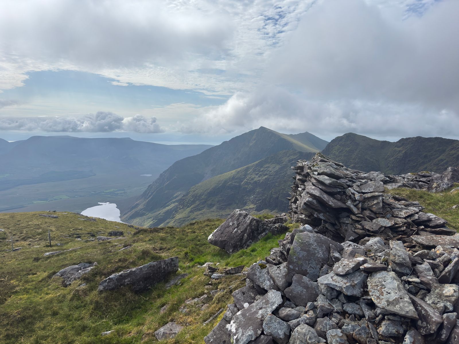 A stone cairn high above corries and mountain lakes