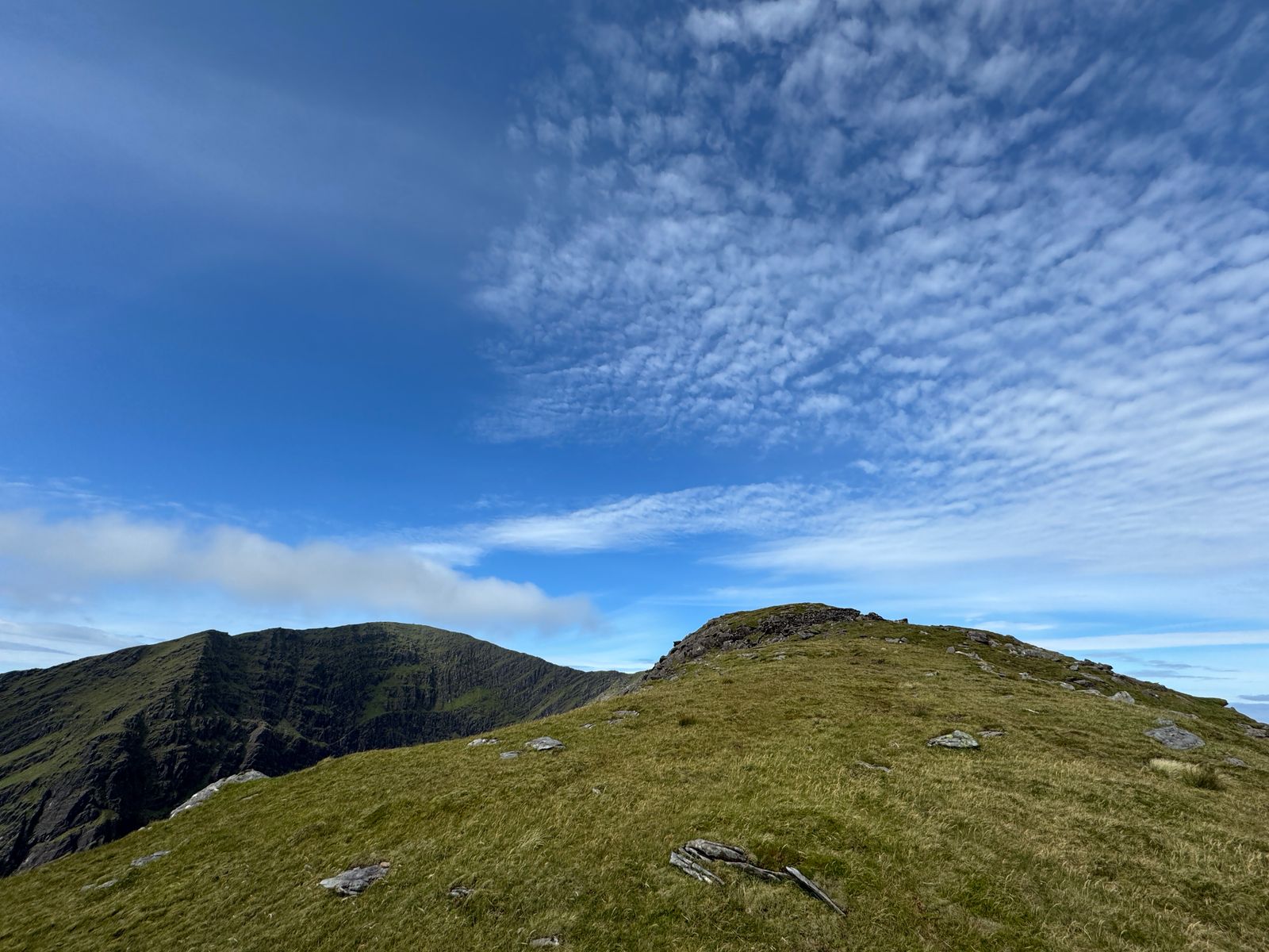 A broad grassy mountain ridge beneath rippled cloud
