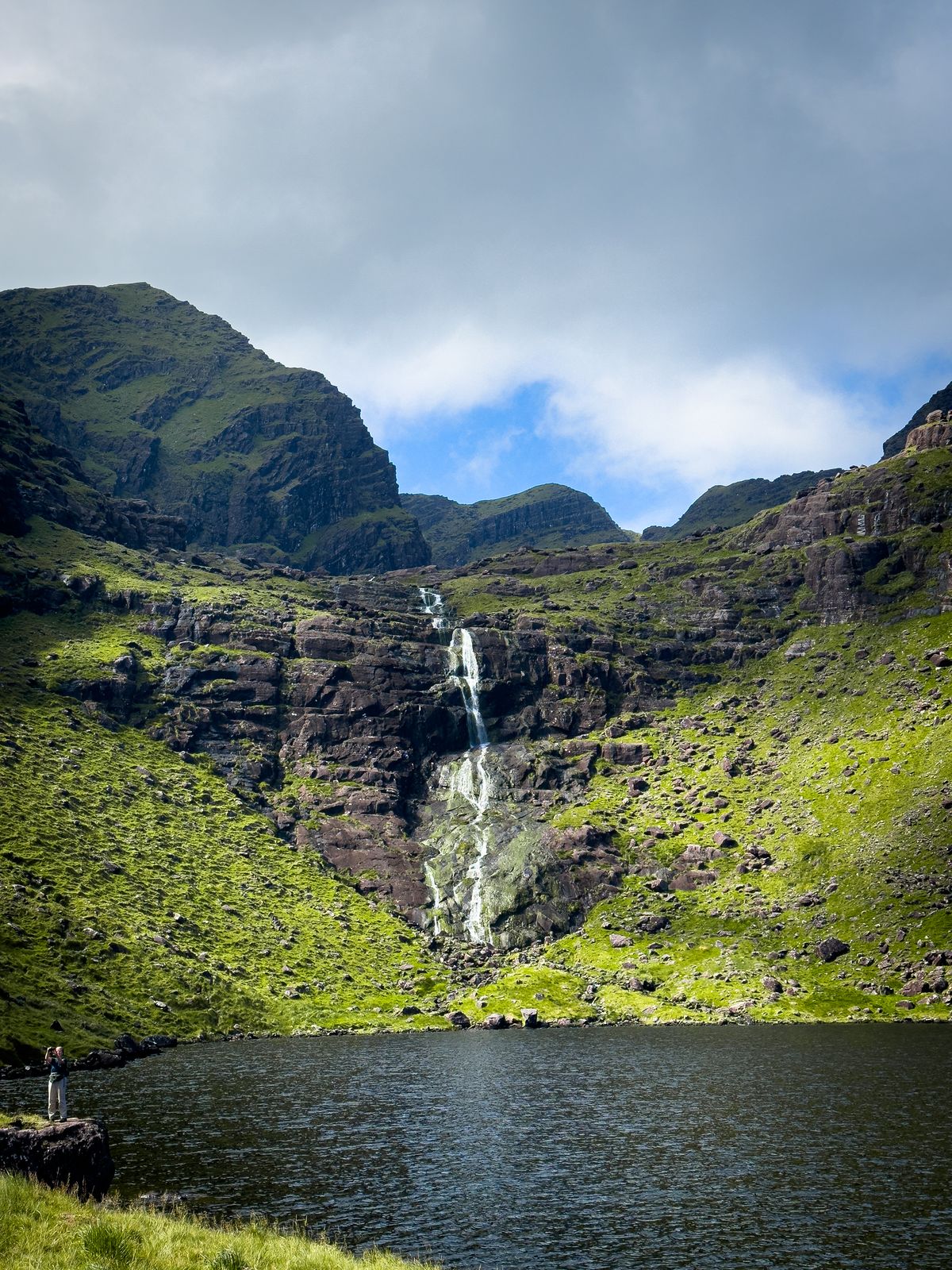 A narrow waterfall dropping down tiered rock in the corrie