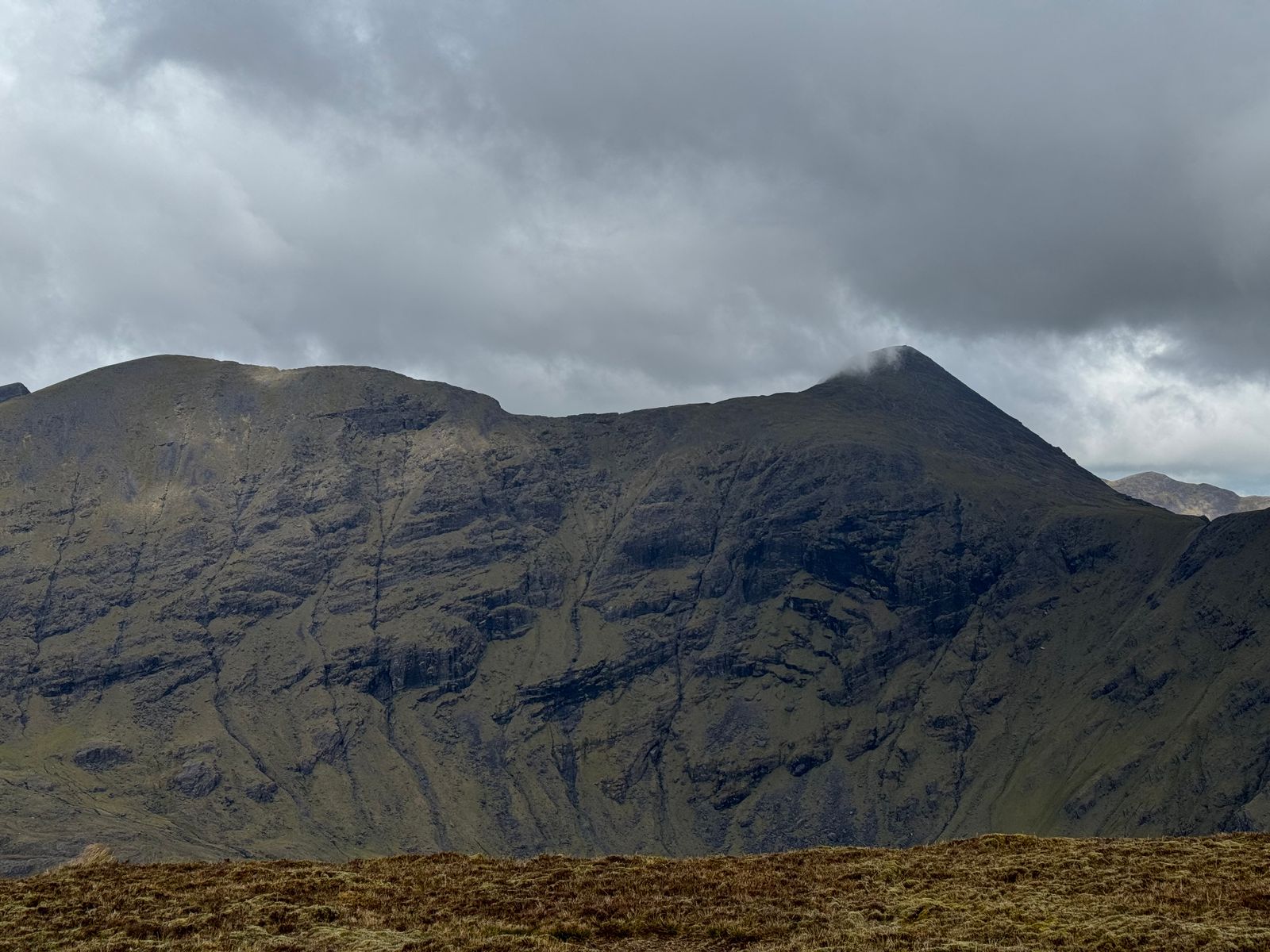 High mountain walls and a pointed summit beneath broken cloud