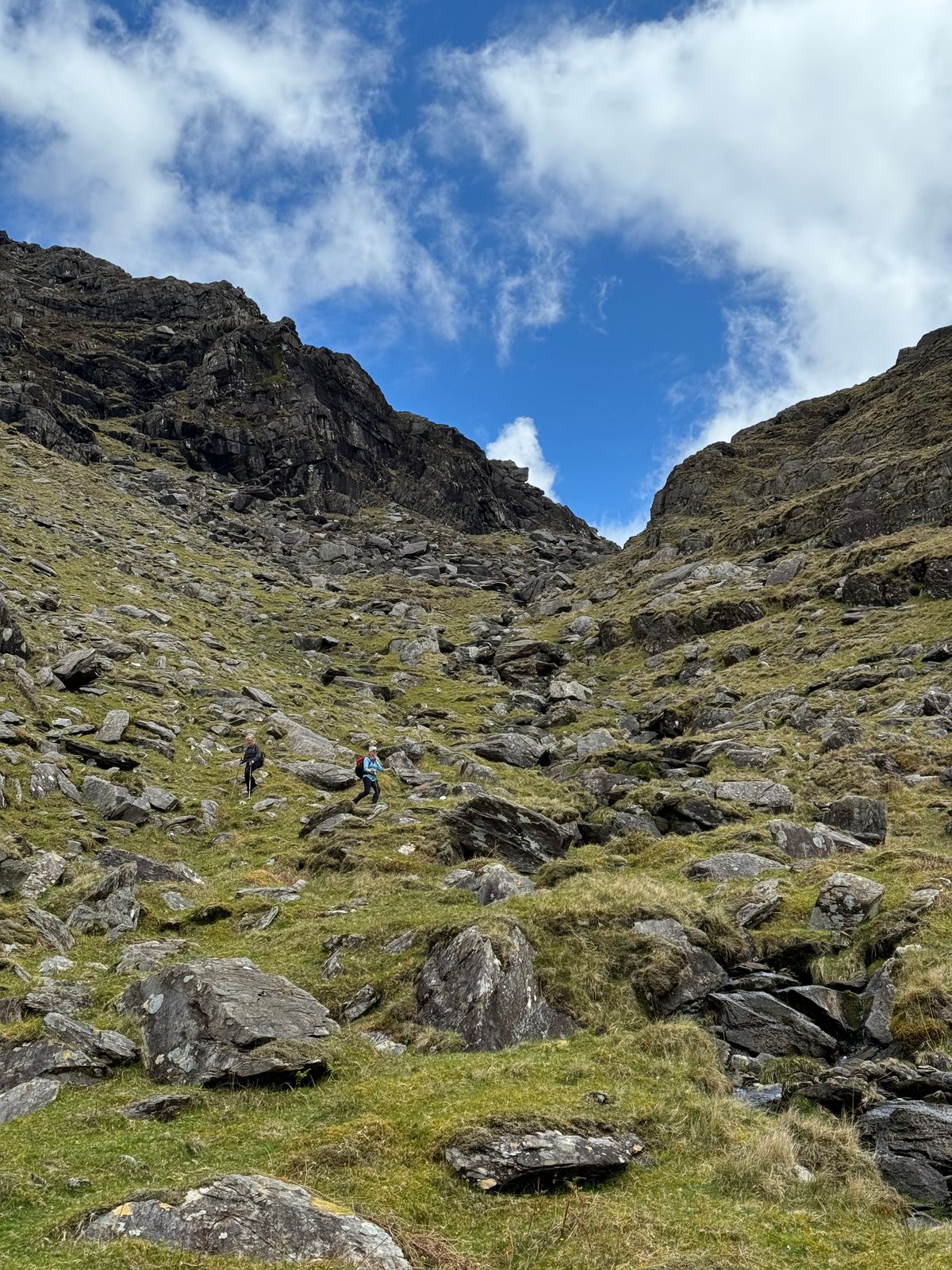 Walkers climbing through a steep rocky gully beneath Bruach na Binne