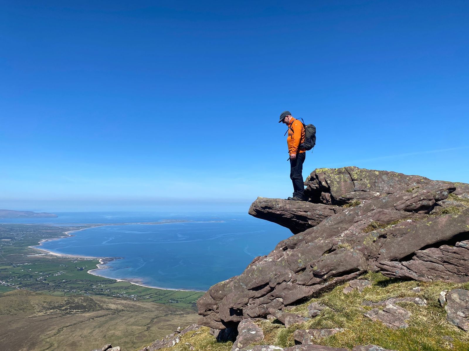 A walker standing on the projecting sandstone ledge known as Fionn Mac Cumhaill’s Chair, high above Tralee Bay