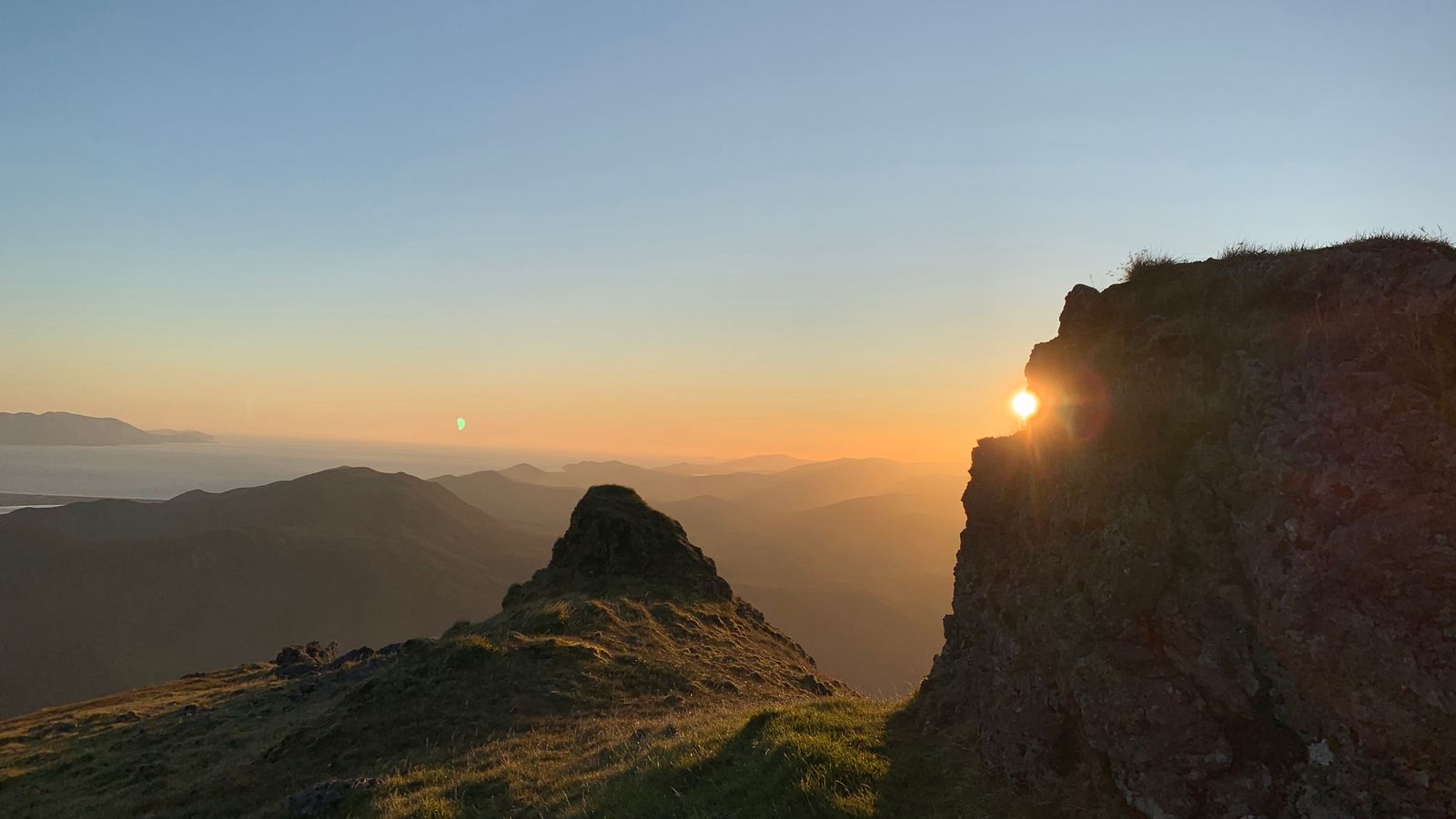 Sunrise shining through a notch in the summit rock