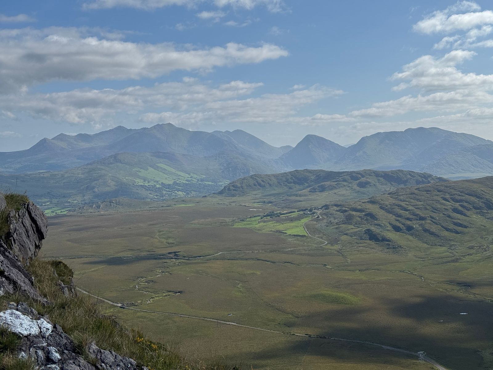 A wide view across dark mountain ground towards the MacGillycuddy’s Reeks
