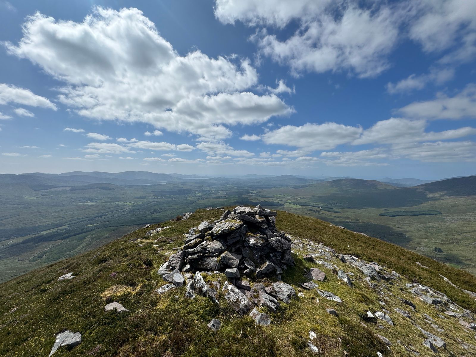 The summit cairn on Colly beneath broken cloud and blue sky