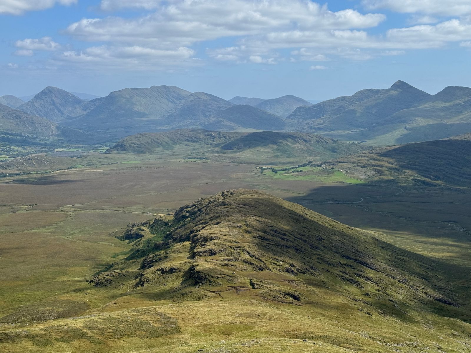 A narrow green ridge descending towards a broad mountain backdrop