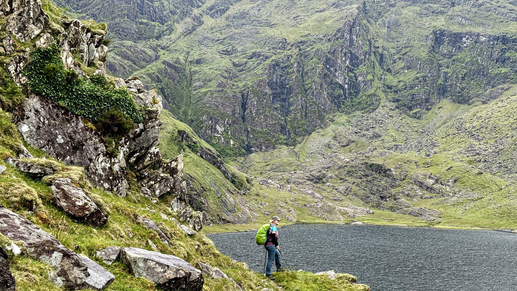 A walker beneath steep corrie cliffs and broken mountain rock