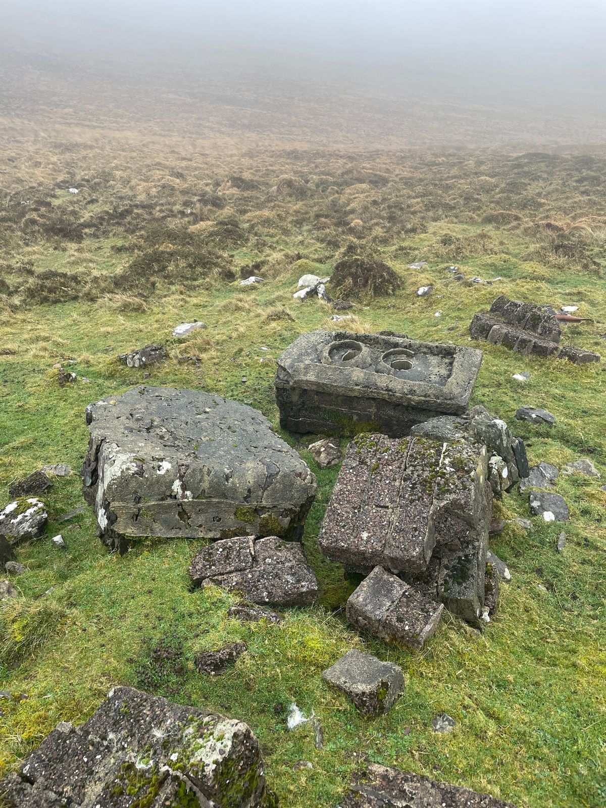 A group of loose and upright stones on rough grassy ground in mist