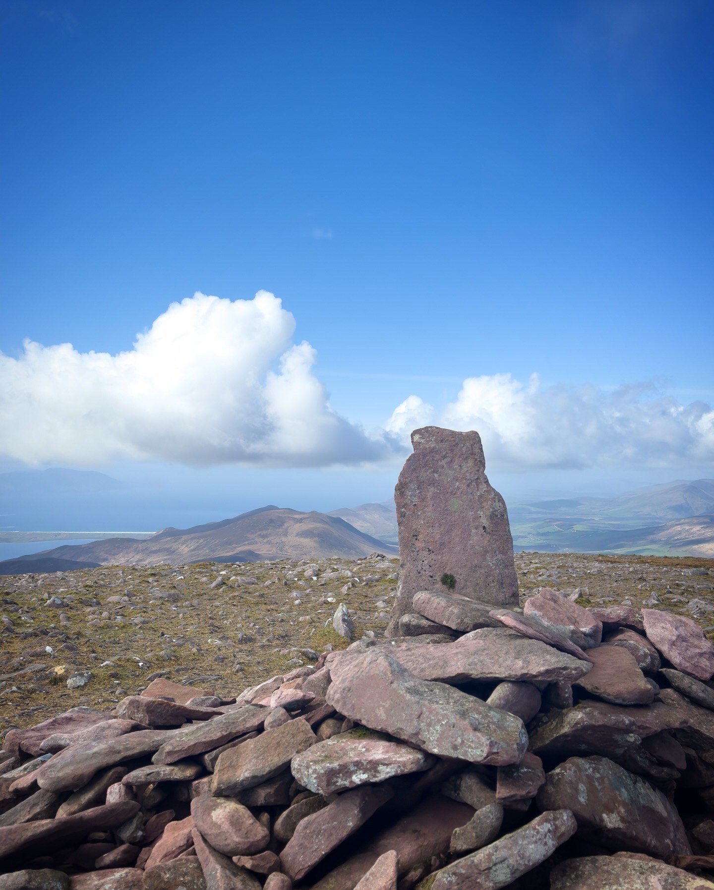 A tall weathered stone on high ground beneath a bright Kerry sky