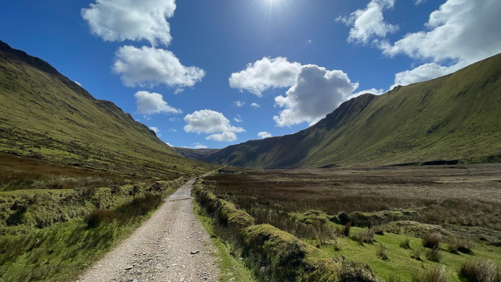 A stony track leading into the steep-sided Macha na Bó valley beneath blue sky