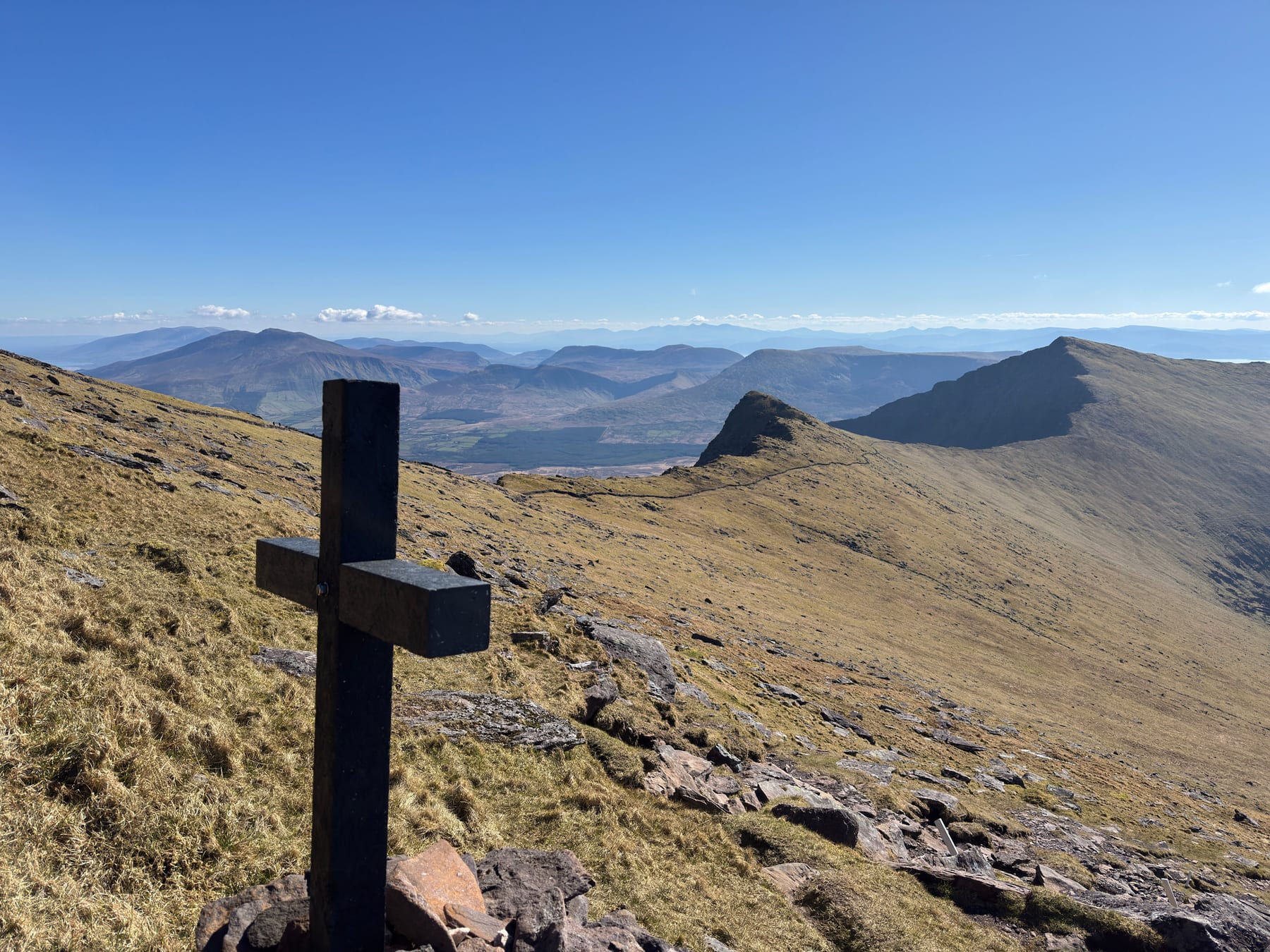 Dark summit cross overlooking the ridges and mountains of the Dingle Peninsula
