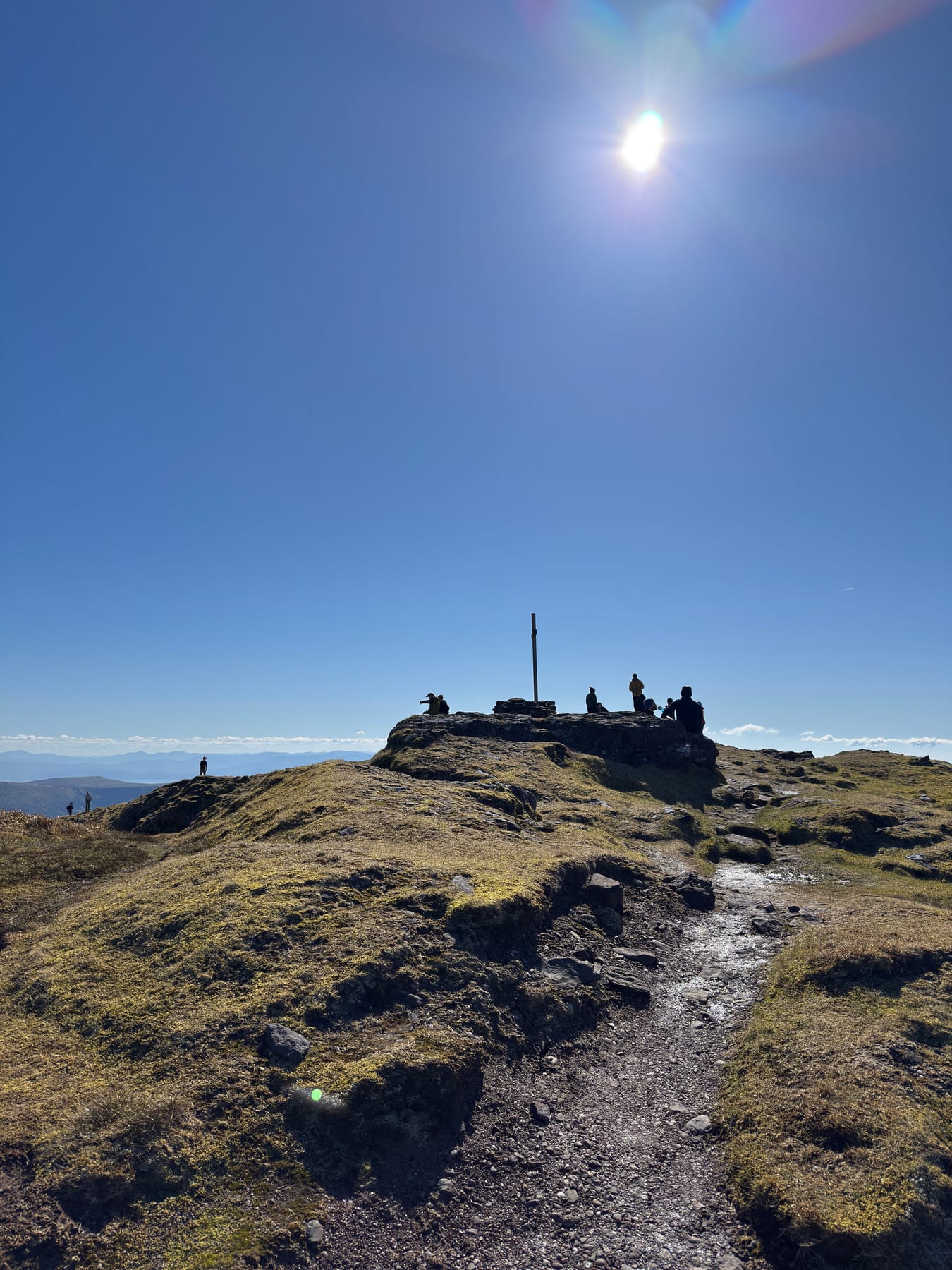 Walkers gathered on the sunlit summit area of Mount Brandon