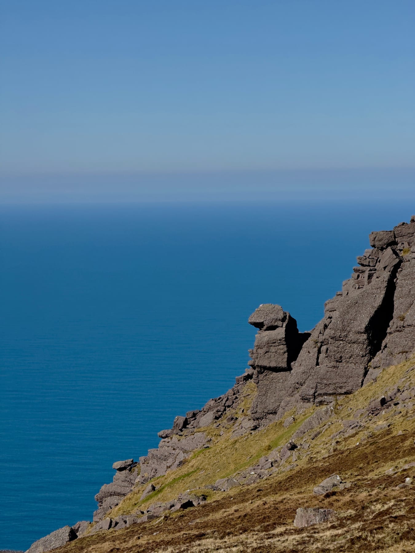 Layered mountain rock rising sharply above the blue Atlantic