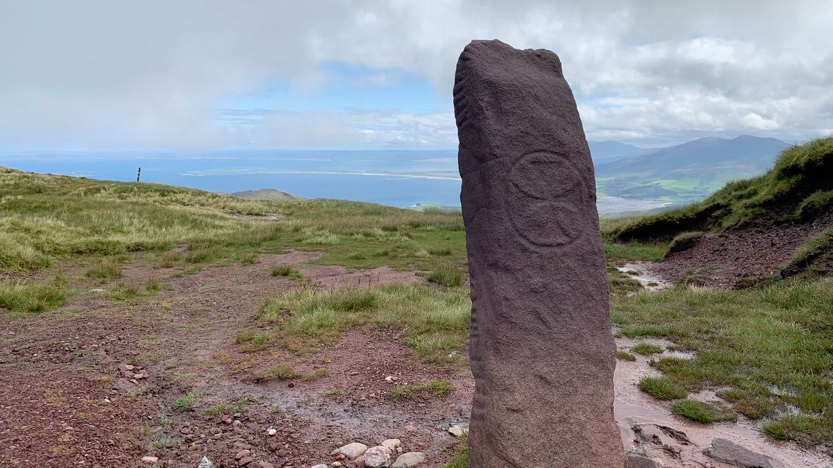 Ogham stone on the Brandon ridge, a cross carved inside a circle on its face and the bay behind
