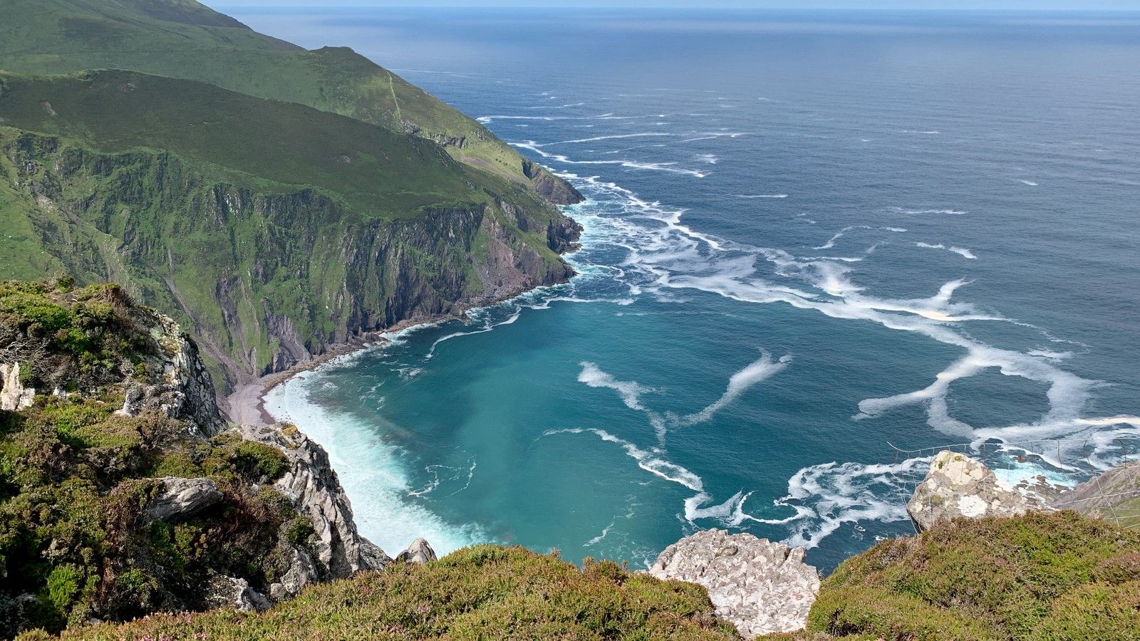 Turquoise Atlantic water and white swell beneath the sheer coastal cliffs