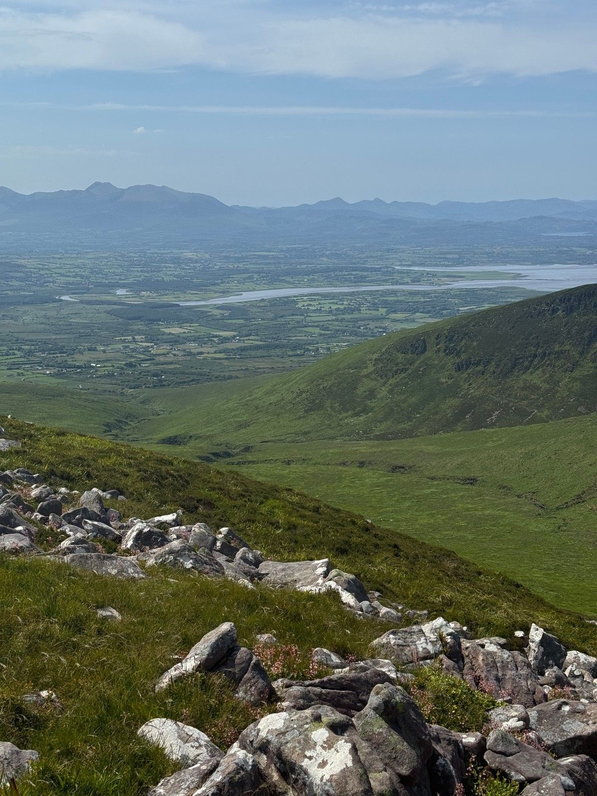 A view from the Slieve Mish slopes across a green valley, Tralee Bay and distant mountains
