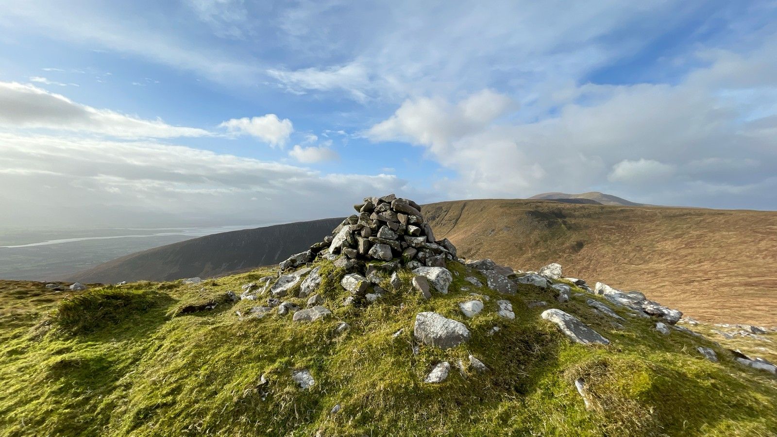 A mountain cairn with the higher Slieve Mish ridge beyond