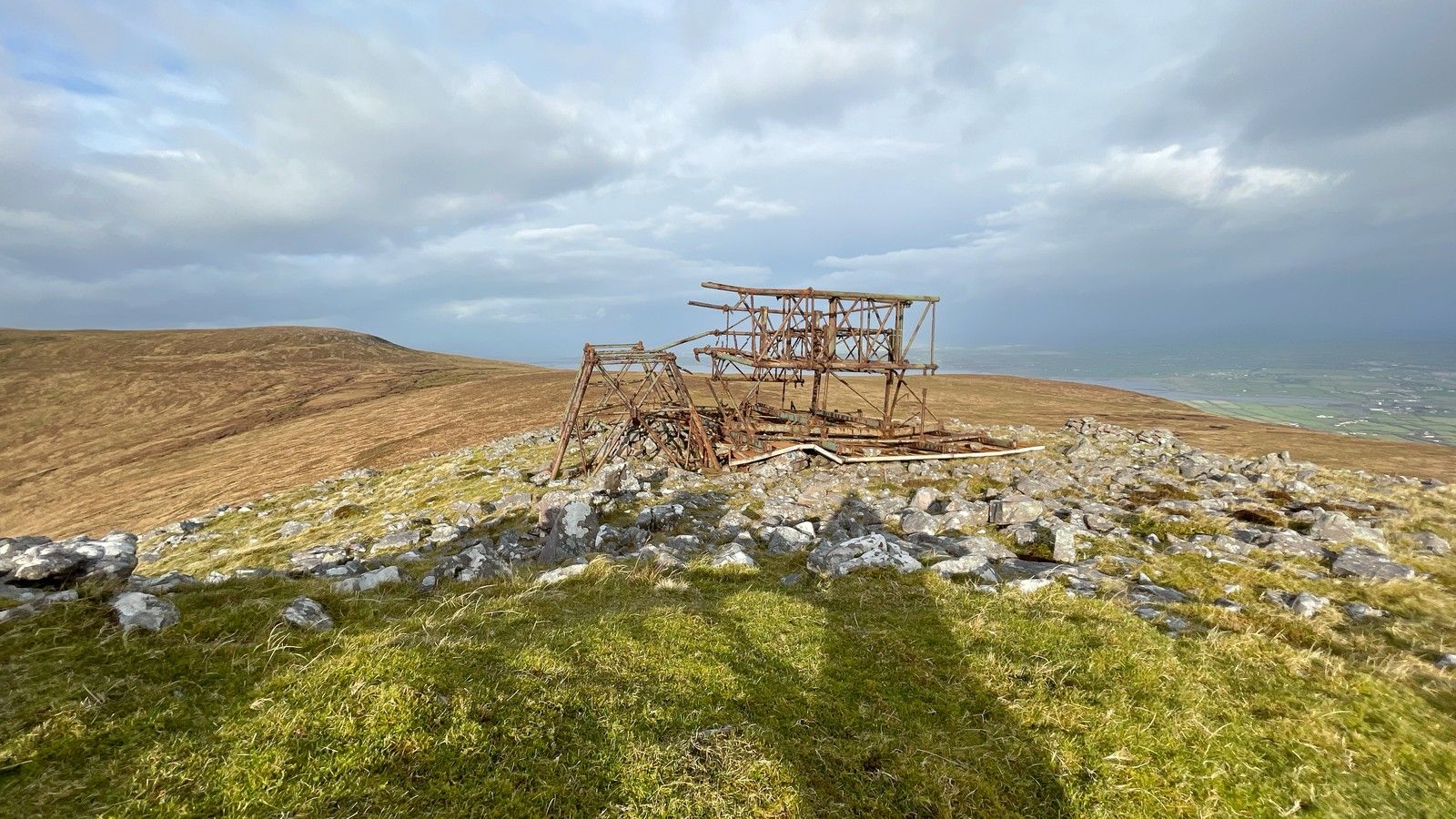 The rusted Iron Man structure surrounded by pale rock and rough grass